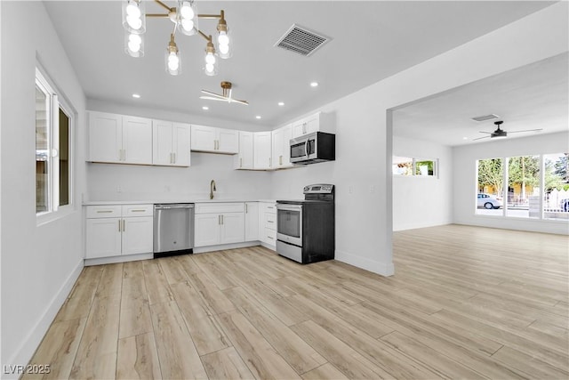 2105 Berkley Ave, Las Vegas, NV 89101 - kitchen featuring stainless steel appliances, a chandelier, light wood-style flooring, white cabinets, and open floor plan