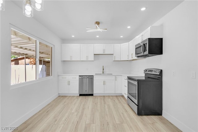 2105 Berkley Ave, Las Vegas, NV 89101 - kitchen with stainless steel appliances, light wood-style flooring, white cabinets, and recessed lighting