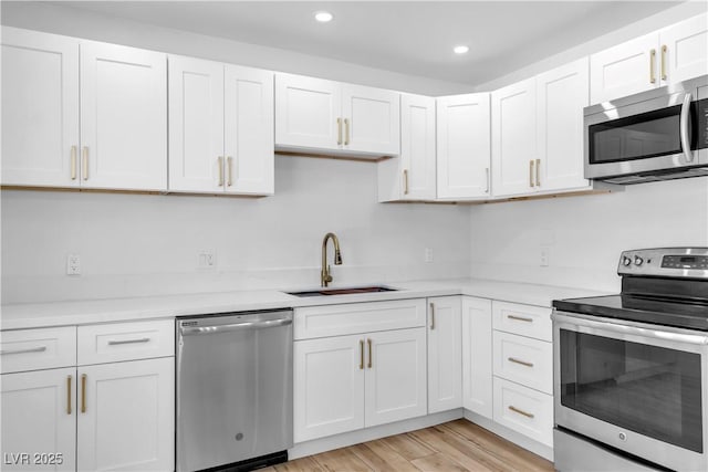 2105 Berkley Ave, Las Vegas, NV 89101 - kitchen featuring appliances with stainless steel finishes, white cabinetry, light countertops, recessed lighting, and light wood-style flooring