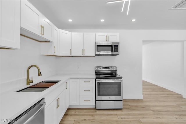 2105 Berkley Ave, Las Vegas, NV 89101 - kitchen with appliances with stainless steel finishes, white cabinetry, light countertops, light wood-style flooring, and recessed lighting