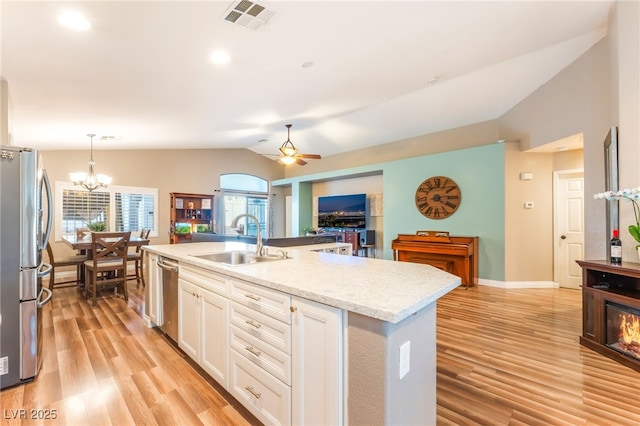 5733 Dazzling Sparks St, North Las Vegas, NV 89031 - kitchen featuring vaulted ceiling, stainless steel appliances, white cabinetry, light wood-style floors, and open floor plan