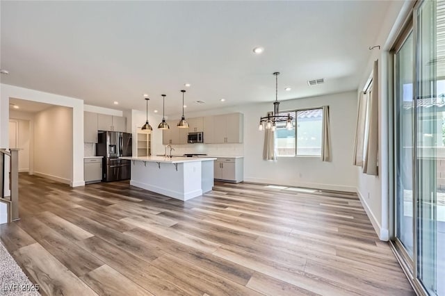 1213 Granite Falls Pl, North Las Vegas, NV 89084 - kitchen featuring appliances with stainless steel finishes, light countertops, light wood-style flooring, gray cabinetry, and a kitchen island with sink