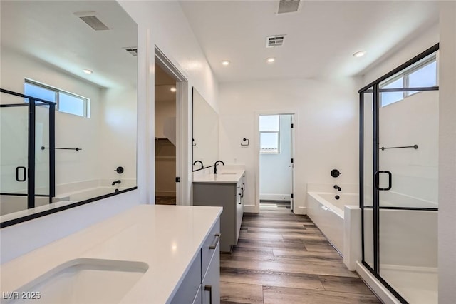 1213 Granite Falls Pl, North Las Vegas, NV 89084 - bathroom featuring a stall shower, two vanities, a garden tub, recessed lighting, and wood finished floors