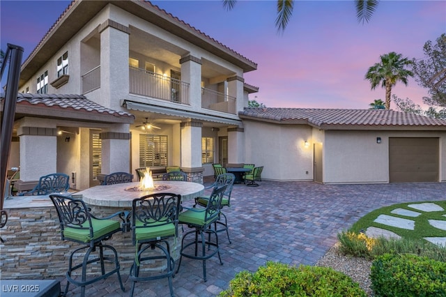 2285 Villefort Ct, Las Vegas, NV 89117 - patio terrace at dusk featuring an outdoor fire pit, a patio, a balcony, an attached garage, and driveway