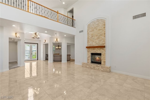 2285 Villefort Ct, Las Vegas, NV 89117 - unfurnished living room with a chandelier, a high ceiling, a fireplace, marble tiled flooring, and french doors
