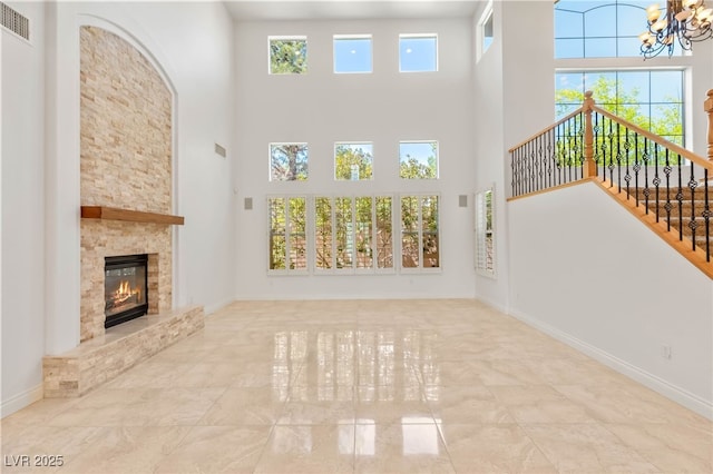 2285 Villefort Ct, Las Vegas, NV 89117 - unfurnished living room with a chandelier, a towering ceiling, a stone fireplace, and stairway