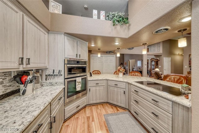 4045 N Chieftain St, Las Vegas, NV 89129 - kitchen with black electric stovetop, double oven, light wood finished floors, pendant lighting, and light stone countertops