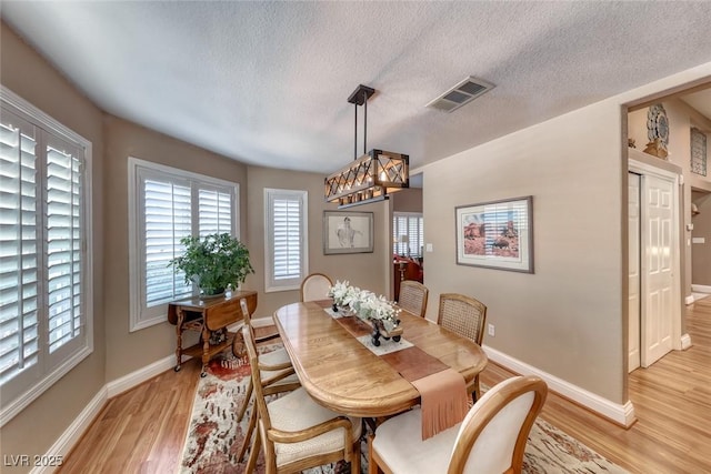 4045 N Chieftain St, Las Vegas, NV 89129 - dining room featuring light wood-style flooring, a textured ceiling, and a chandelier