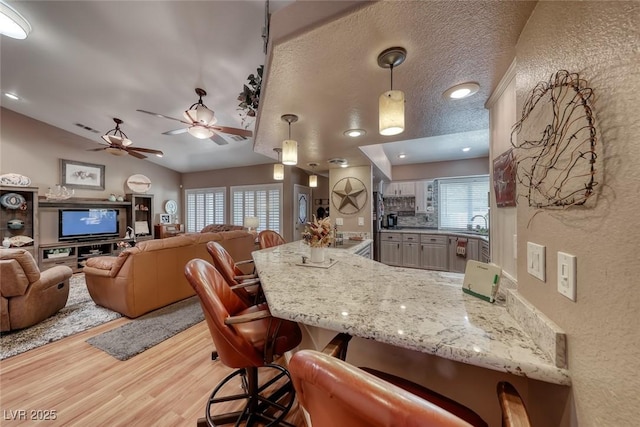 4045 N Chieftain St, Las Vegas, NV 89129 - kitchen with a peninsula, wood finished floors, healthy amount of natural light, a ceiling fan, and lofted ceiling