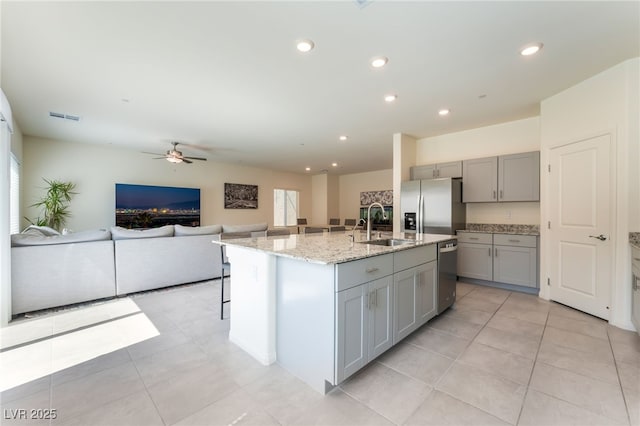 7211 Alabaster Peak St, Las Vegas, NV 89166 - kitchen with gray cabinets, stainless steel appliances, open floor plan, ceiling fan, and light stone counters