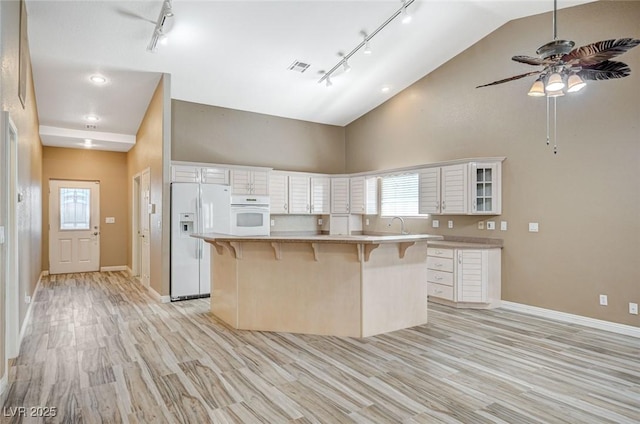 819 Sandsprings St, Henderson, NV 89011 - kitchen featuring white appliances, track lighting, a breakfast bar, high vaulted ceiling, and white cabinetry