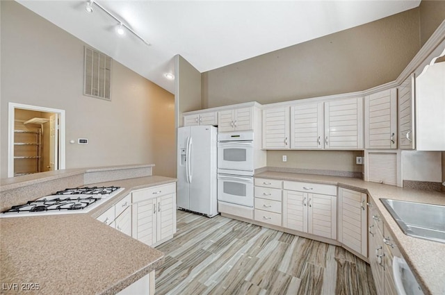 819 Sandsprings St, Henderson, NV 89011 - kitchen with white appliances, high vaulted ceiling, light countertops, white cabinetry, and light wood-style floors