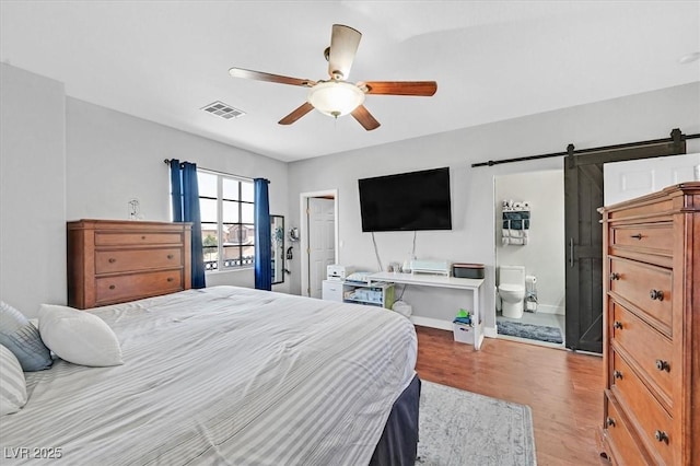 3591 Gloucester Gate St, Las Vegas, NV 89122 - bedroom with wood finished floors, a barn door, ceiling fan, and ensuite bathroom