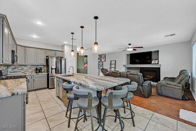 3591 Gloucester Gate St, Las Vegas, NV 89122 - kitchen with gray cabinets, appliances with stainless steel finishes, light tile patterned flooring, ceiling fan, and tasteful backsplash