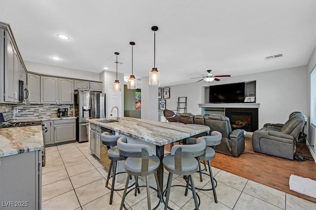 3591 Gloucester Gate St, Las Vegas, NV 89122 - kitchen featuring gray cabinetry, stainless steel appliances, light tile patterned floors, a ceiling fan, and tasteful backsplash