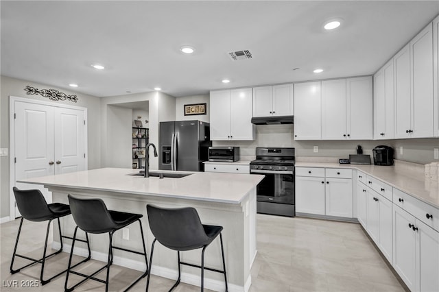 8346 Vinamala Ave, Las Vegas, NV 89149 - kitchen featuring stainless steel range with gas stovetop, under cabinet range hood, fridge with ice dispenser, an island with sink, and white cabinetry
