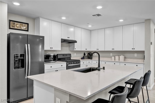 8346 Vinamala Ave, Las Vegas, NV 89149 - kitchen with stainless steel appliances, a breakfast bar, white cabinetry, under cabinet range hood, and recessed lighting