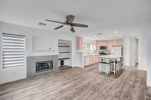 5823 Rose Sage St, North Las Vegas, NV 89031 - kitchen with white appliances, light countertops, a ceiling fan, light wood-style floors, and a kitchen bar