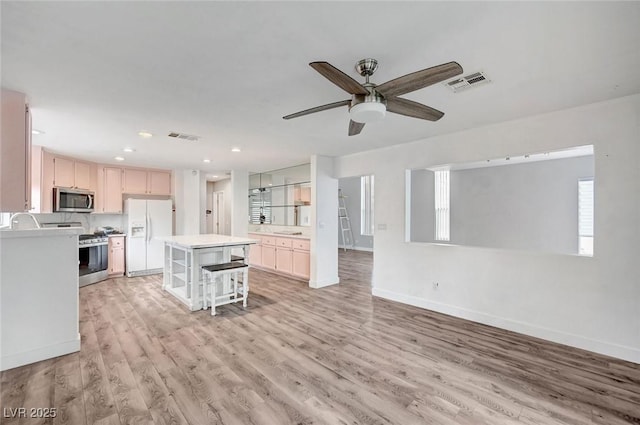 5823 Rose Sage St, North Las Vegas, NV 89031 - kitchen with stainless steel microwave, white refrigerator with ice dispenser, range with gas cooktop, ceiling fan, and light countertops