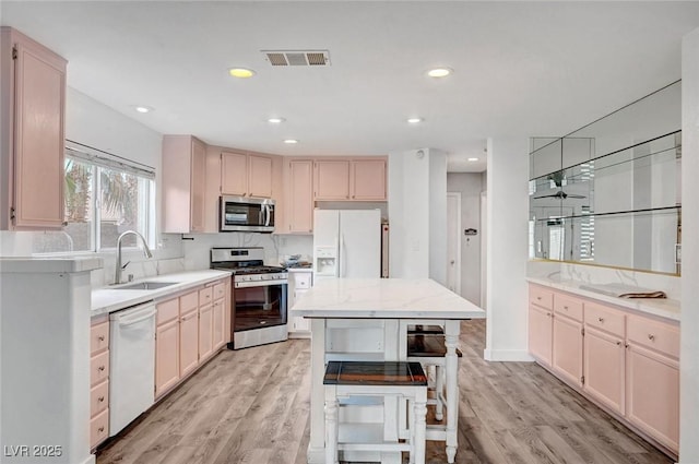 5823 Rose Sage St, North Las Vegas, NV 89031 - kitchen with appliances with stainless steel finishes, light wood-style flooring, a kitchen island, recessed lighting, and decorative backsplash