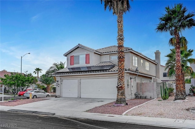 5823 Rose Sage St, North Las Vegas, NV 89031 - view of front facade featuring an attached garage, driveway, stucco siding, a tiled roof, and roof mounted solar panels