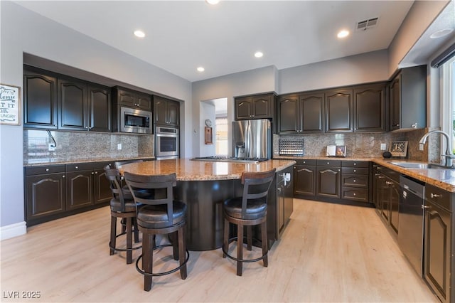 352 Angels Trace Ct, Las Vegas, NV 89148 - kitchen with stainless steel appliances, a kitchen island, light wood-type flooring, light stone countertops, and recessed lighting