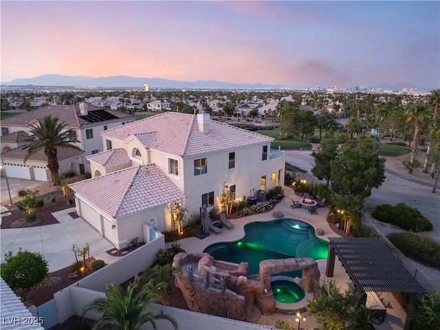352 Angels Trace Ct, Las Vegas, NV 89148 - pool at dusk featuring a fenced backyard, a pool with connected hot tub, a mountain view, and a patio