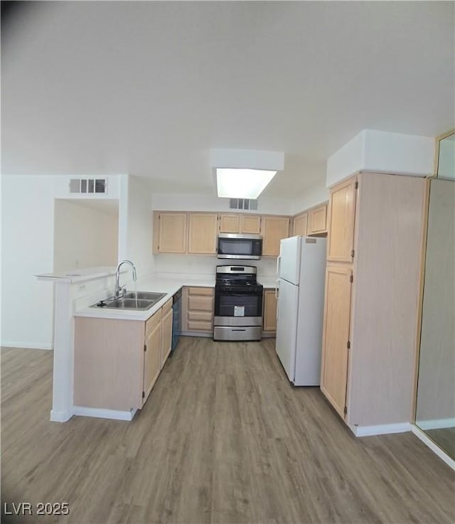 3425 E Russell Rd Unit 265, Las Vegas, NV 89120 - kitchen featuring stainless steel appliances, a peninsula, light wood-type flooring, light brown cabinets, and light countertops