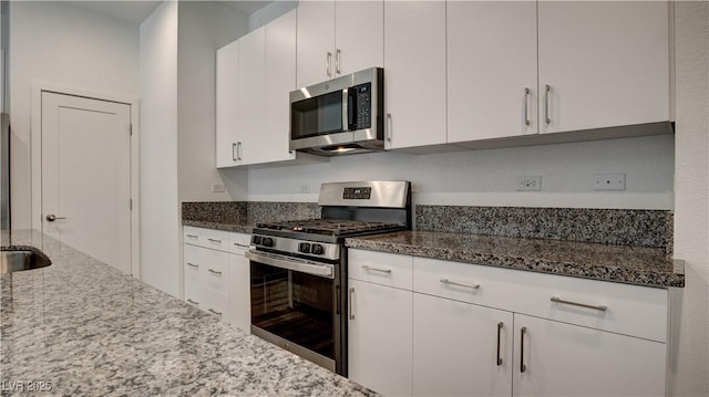 3219 Timorasso Ave, Henderson, NV 89044 - kitchen featuring appliances with stainless steel finishes, dark stone counters, and white cabinetry