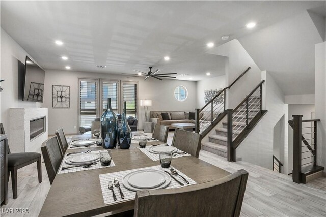 8175 Caldera Creek St, Las Vegas, NV 89113 - dining room with light wood-style flooring, a glass covered fireplace, ceiling fan, recessed lighting, and stairway