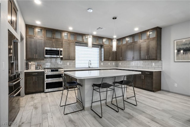 8175 Caldera Creek St, Las Vegas, NV 89113 - kitchen with appliances with stainless steel finishes, a kitchen bar, light wood-type flooring, light countertops, and decorative backsplash