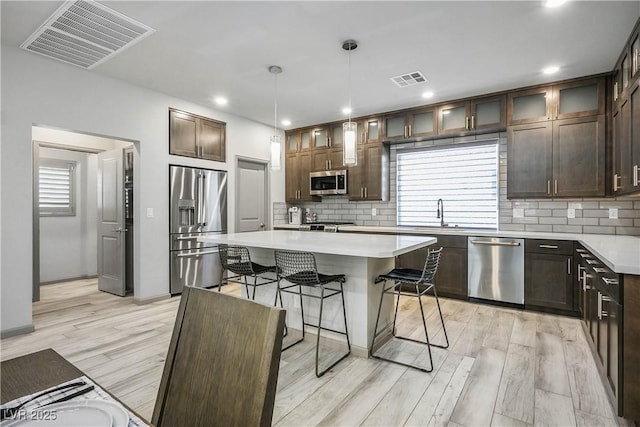 8175 Caldera Creek St, Las Vegas, NV 89113 - kitchen with appliances with stainless steel finishes, a breakfast bar area, tasteful backsplash, light wood-style flooring, and recessed lighting