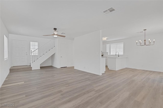 3741 Cactus Wheel Ct, Las Vegas, NV 89129 - unfurnished living room featuring a chandelier, light wood finished floors, a ceiling fan, and stairs