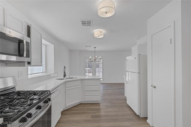 3741 Cactus Wheel Ct, Las Vegas, NV 89129 - kitchen with appliances with stainless steel finishes, a peninsula, white cabinetry, a chandelier, and light countertops