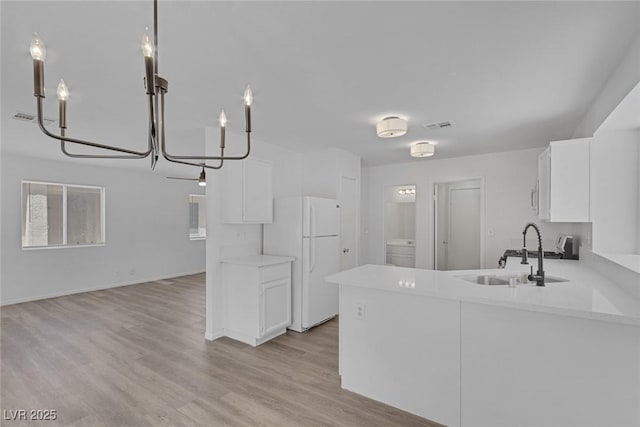 3741 Cactus Wheel Ct, Las Vegas, NV 89129 - kitchen with freestanding refrigerator, white cabinets, a chandelier, light countertops, and light wood-style flooring