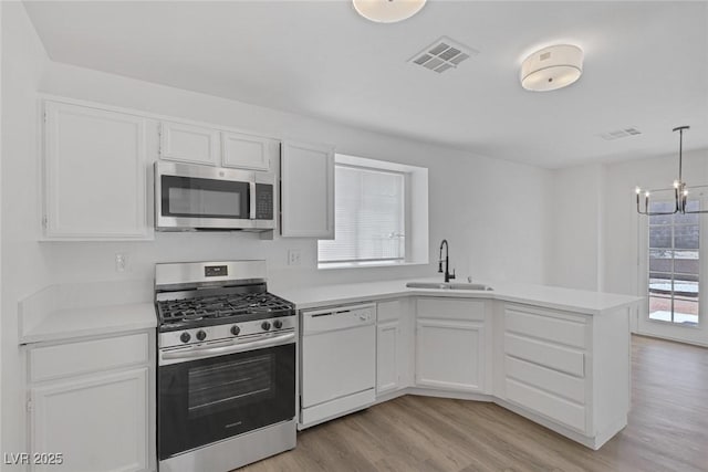 3741 Cactus Wheel Ct, Las Vegas, NV 89129 - kitchen featuring appliances with stainless steel finishes, light wood finished floors, a peninsula, and light countertops