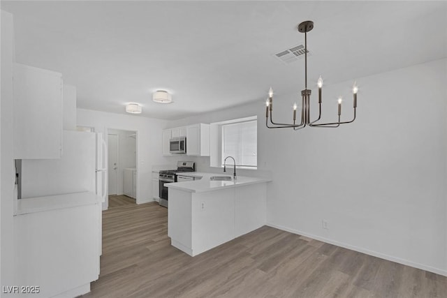 3741 Cactus Wheel Ct, Las Vegas, NV 89129 - kitchen with stainless steel appliances, a chandelier, a peninsula, light wood finished floors, and light countertops
