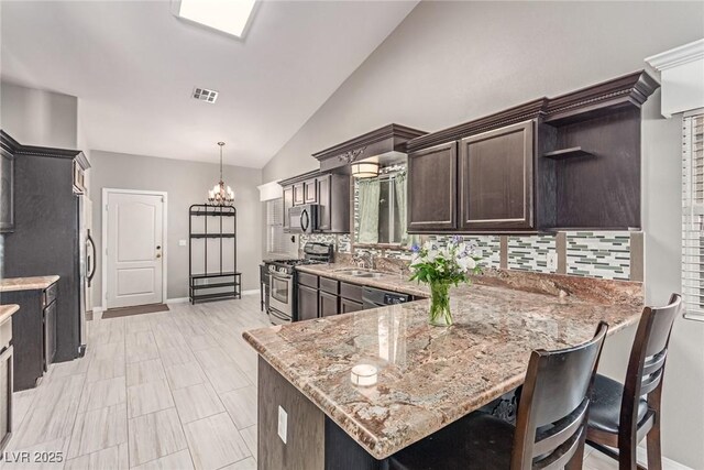 1761 Summerwood Cir, Henderson, NV 89012 - kitchen with backsplash, appliances with stainless steel finishes, vaulted ceiling, dark brown cabinets, and light stone countertops