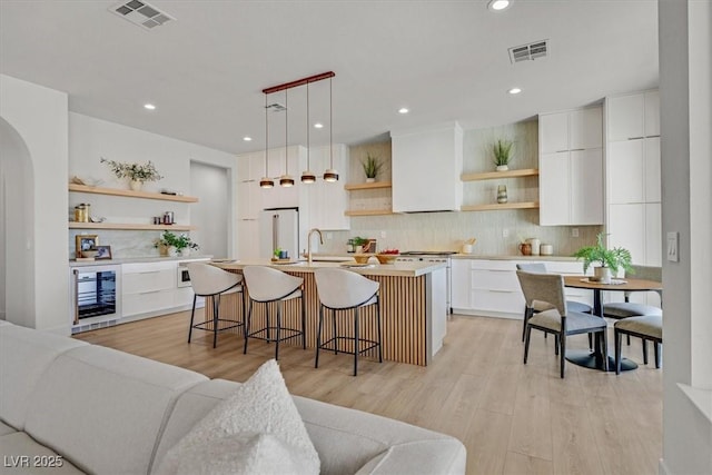 328 Hedgehope Dr, Las Vegas, NV 89183 - kitchen with open shelves, wine cooler, freestanding refrigerator, tasteful backsplash, and a breakfast bar area