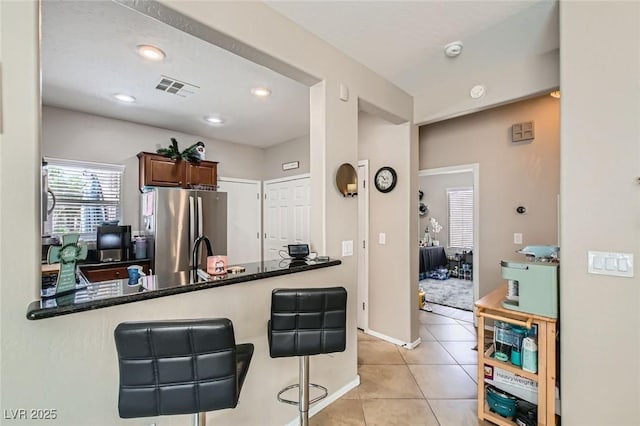 7717 Pine Warbler Way N, Las Vegas, NV 89084 - kitchen with freestanding refrigerator, light tile patterned floors, a kitchen breakfast bar, recessed lighting, and a peninsula