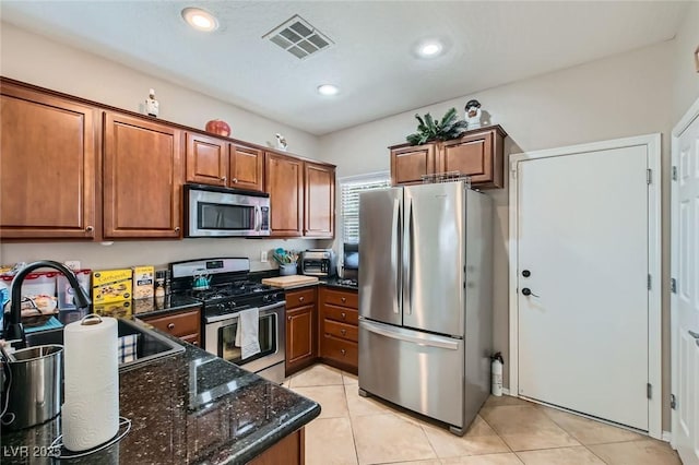 7717 Pine Warbler Way N, Las Vegas, NV 89084 - kitchen with stainless steel appliances, brown cabinets, dark stone counters, light tile patterned flooring, and recessed lighting