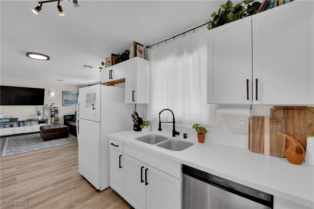 3509 Navajo Way, Las Vegas, NV 89108 - kitchen with stainless steel dishwasher, light countertops, freestanding refrigerator, and white cabinets