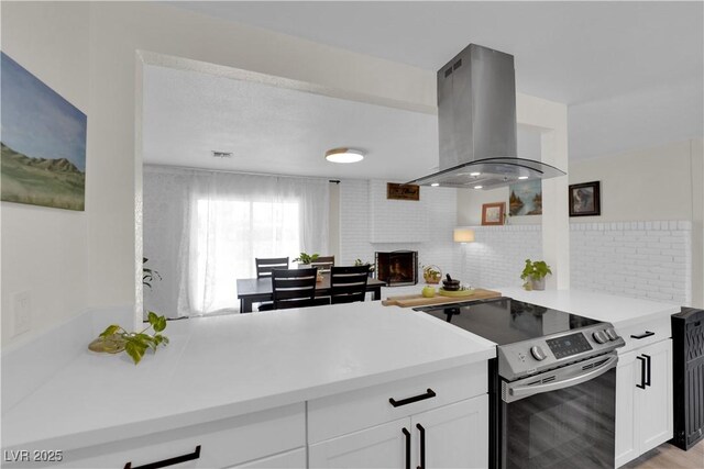 3509 Navajo Way, Las Vegas, NV 89108 - kitchen with stainless steel range with electric cooktop, island range hood, white cabinetry, and light countertops