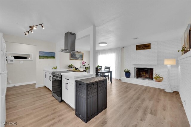 3509 Navajo Way, Las Vegas, NV 89108 - kitchen with stainless steel range with electric stovetop, island range hood, light countertops, light wood finished floors, and open floor plan