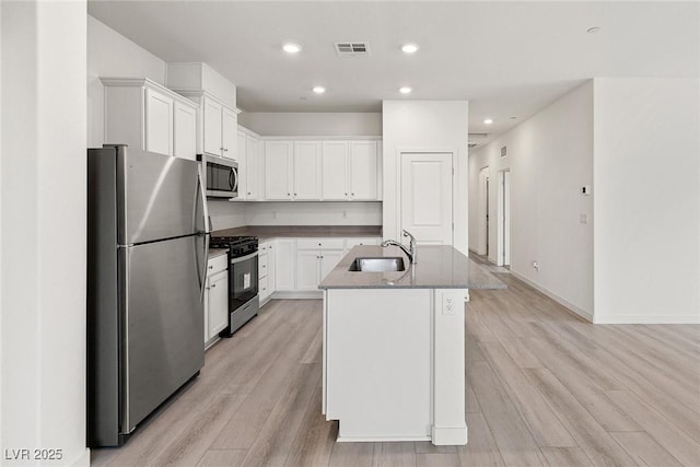 2721 Avril Point St, Las Vegas, NV 89156 - kitchen featuring appliances with stainless steel finishes, light wood-style floors, white cabinets, a center island with sink, and recessed lighting