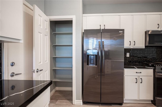 2545 Divine Sky Dr, Henderson, NV 89044 - kitchen with appliances with stainless steel finishes, dark countertops, light wood-style flooring, white cabinetry, and decorative backsplash