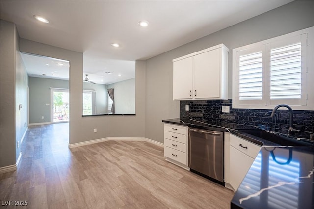 2545 Divine Sky Dr, Henderson, NV 89044 - kitchen featuring stainless steel dishwasher, light wood finished floors, dark countertops, white cabinets, and decorative backsplash