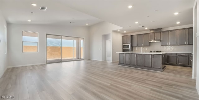 765 Cloud Creek St, Henderson, NV 89011 - kitchen featuring open floor plan, built in microwave, under cabinet range hood, lofted ceiling, and light countertops