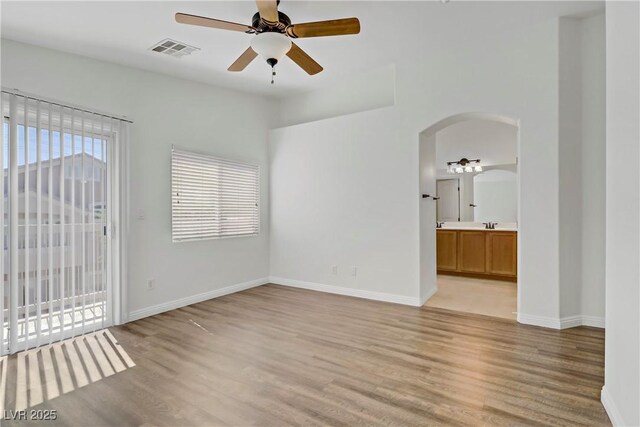 10062 Aspen Rose St Unit 103, Las Vegas, NV 89183 - empty room featuring a ceiling fan, arched walkways, and light wood-style flooring