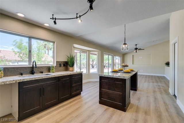 9800 Rosamond Dr, Las Vegas, NV 89134 - kitchen featuring light wood-type flooring, backsplash, light stone countertops, a kitchen island, and hanging light fixtures